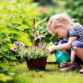 Cute little girl watering plants in the garden