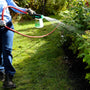 Gardener switching between fan, cone, and stream patterns while treating shrubs.