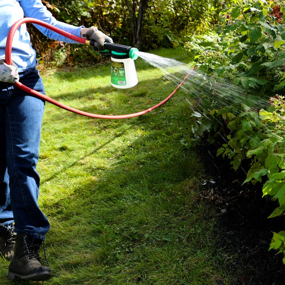 Gardener switching between fan, cone, and stream patterns while treating shrubs.