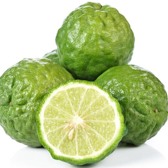 small pile of kaffir limes thai limes one cut to show green flesh